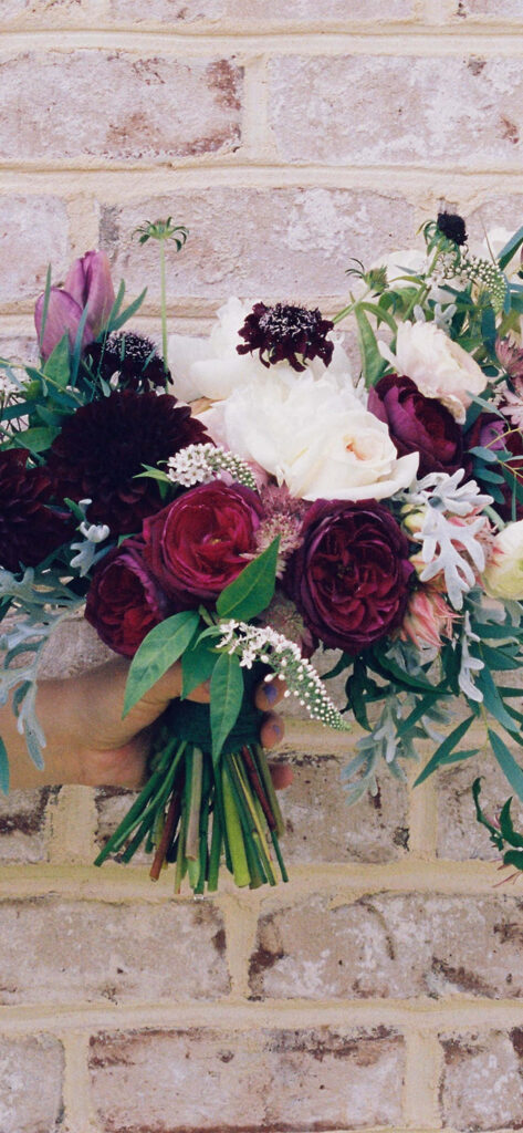 Vibrant Mixed Flower Bouquet Against Rustic Brick Wall Background Wallpaper