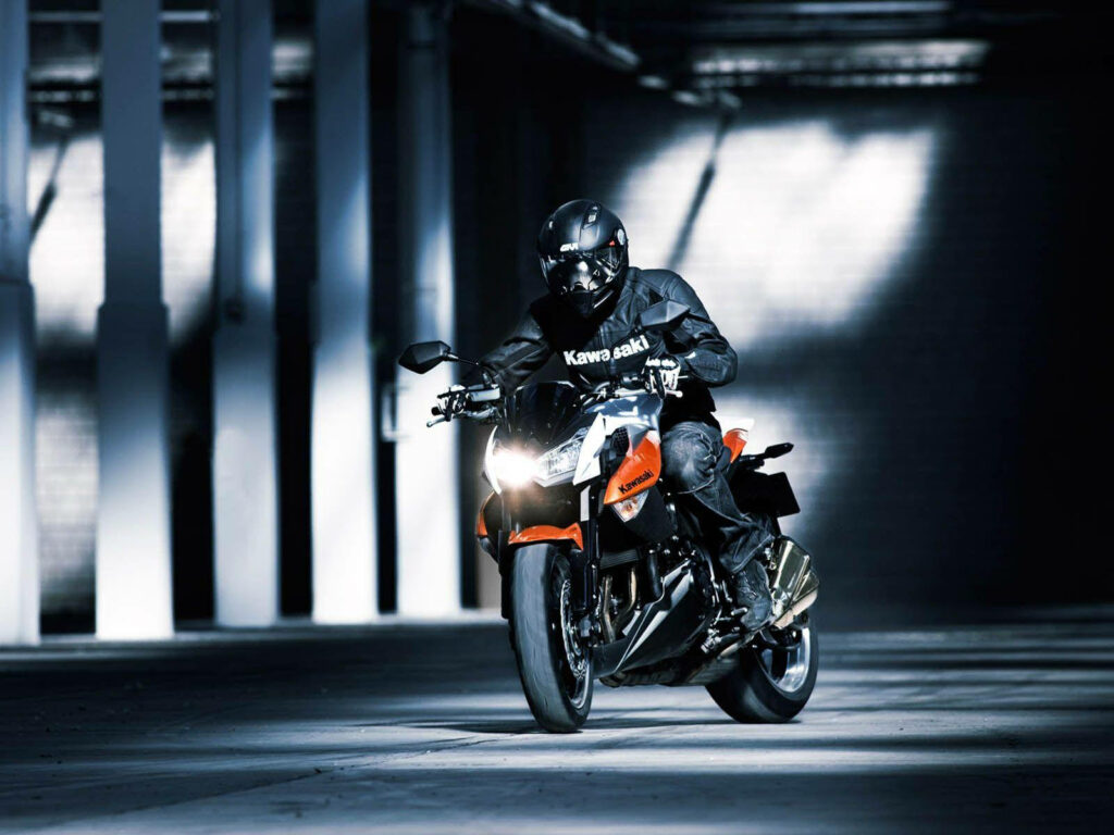 Vibrant Motorcyclist Wallpaper: Intense Bike Scene in Dim Parking