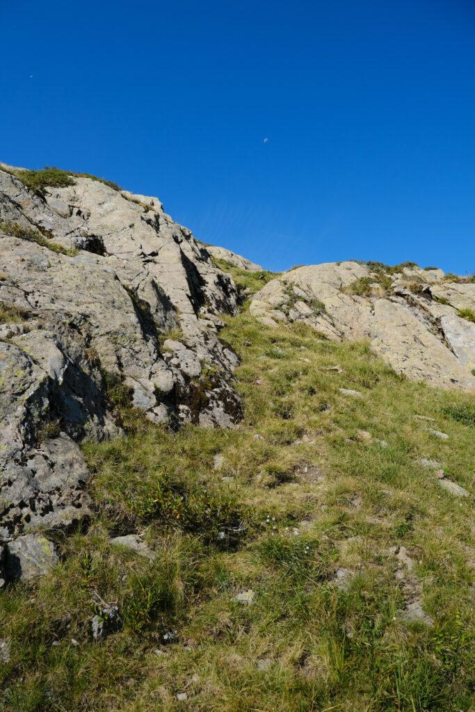 Vibrant mountain landscape with rocky slopes and green grass under clear blue sky wallpaper background