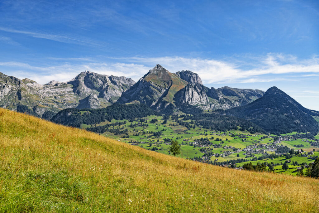 Vibrant wallpaper of rugged mountains lush green valley and grassy slope under bright blue sky