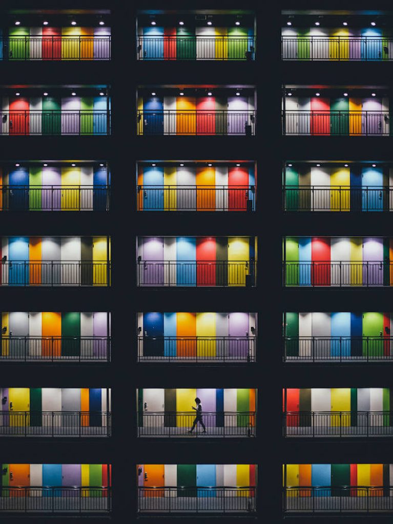 Night urban iOS wallpaper with colorful doors and silhouette on illuminated building facade