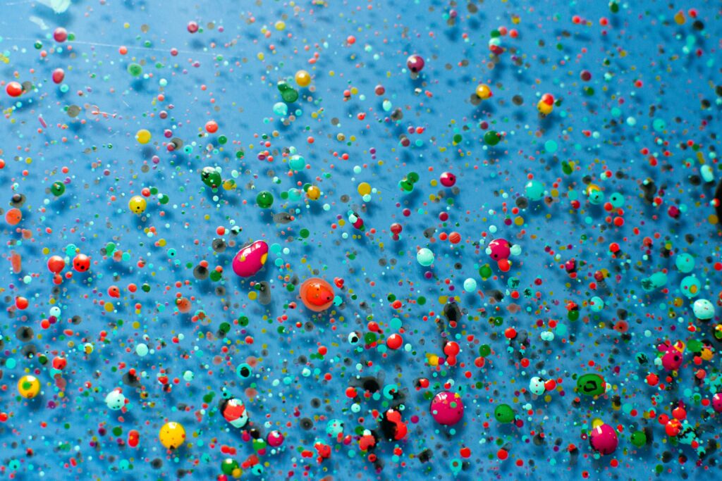 Vibrant Multicolored Paint Drop Wallpaper on Blue Background