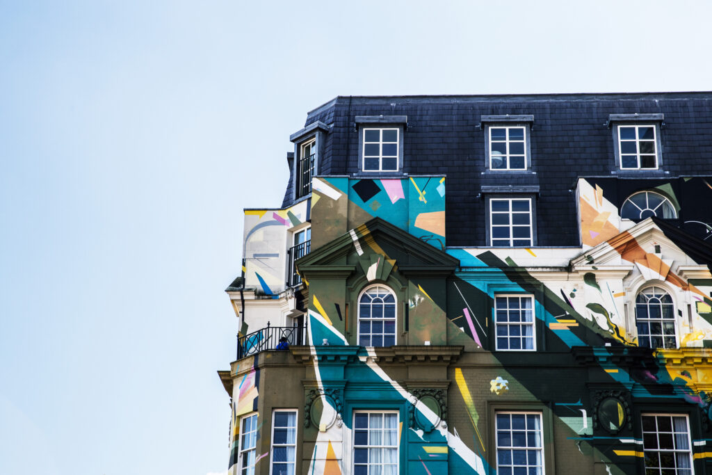 Vibrant Mural on Classic Building: Modern Art Meets Tradition Wallpaper