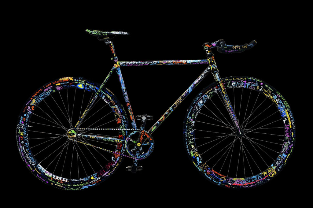 Sleek bicycle with vibrant neon doodles and colorful graffiti designs on black background wallpaper