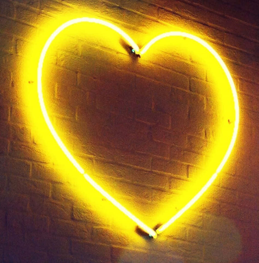 Artistic Wallpaper: Glowing Orange Heart Neon Light on Brick Wall