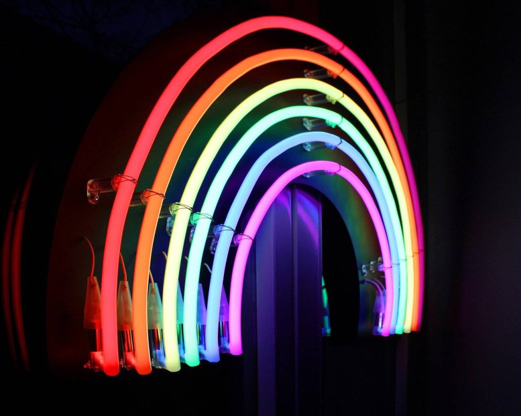 Vibrant neon rainbow arch glowing against dark background modern colorful wallpaper design