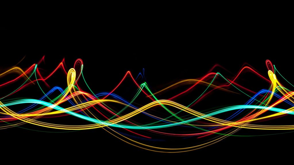 Neon light trails wallpaper with vibrant red yellow green cyan waves on a black background