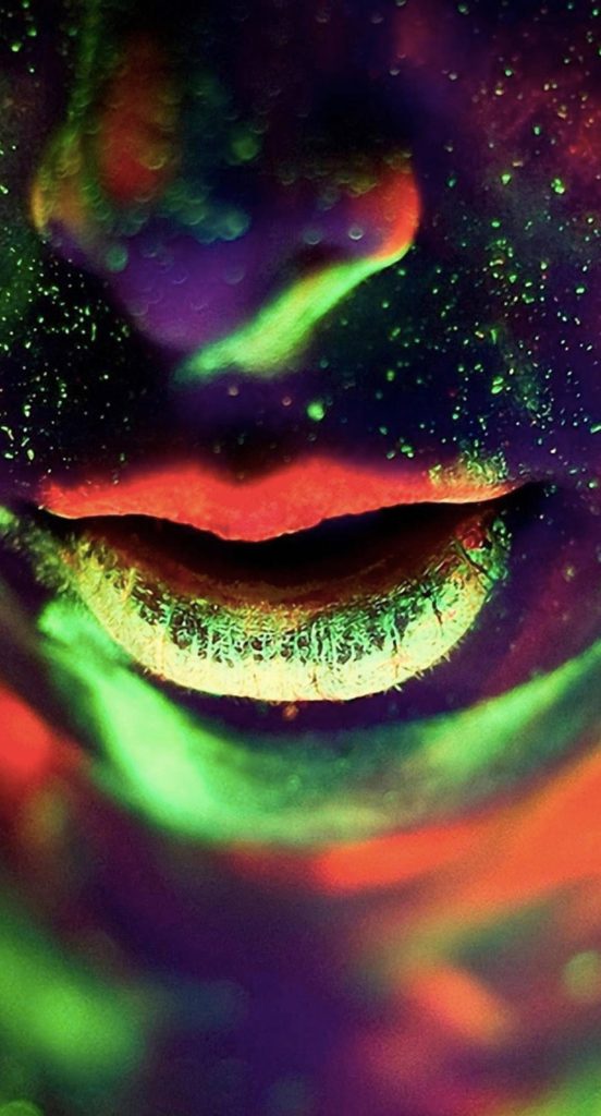 Macro close-up of lips with vibrant neon green and red fluorescent paint on dark background wallpaper