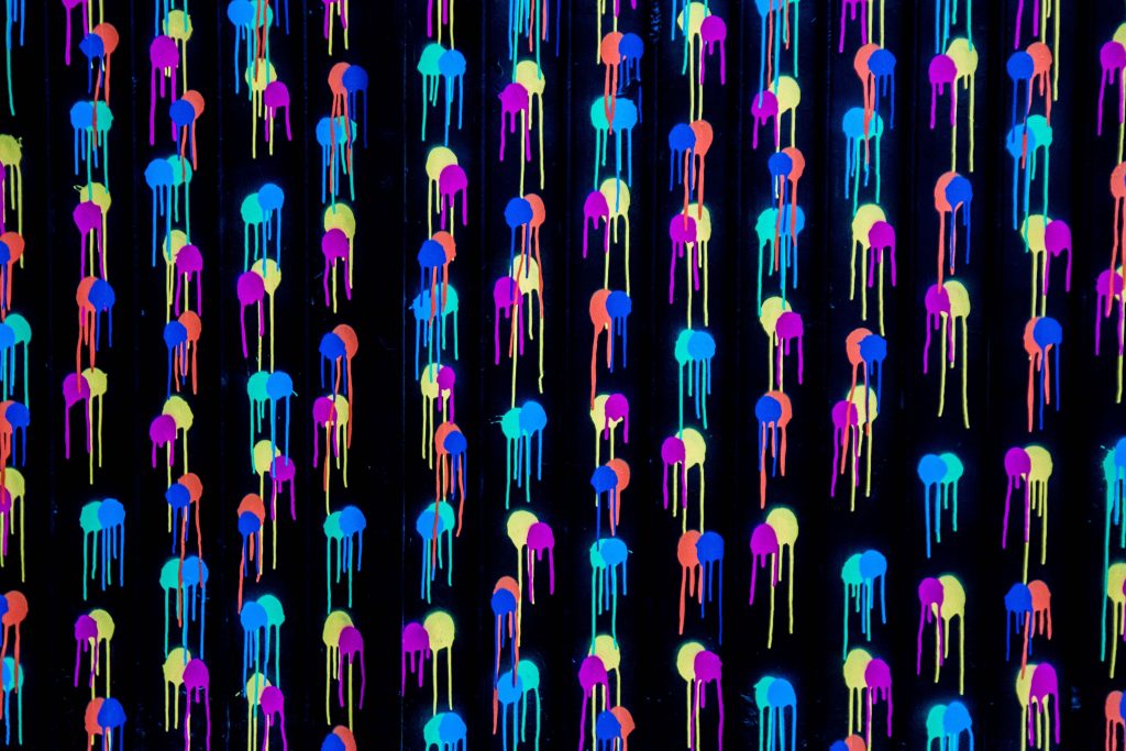 Vibrant neon paint drip wallpaper with jellyfish-like blobs on black for modern decor.
