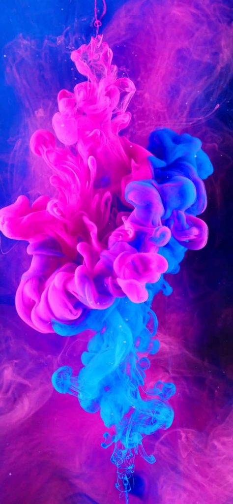 Vibrant neon pink and electric blue ink swirling in clear liquid abstract wallpaper background