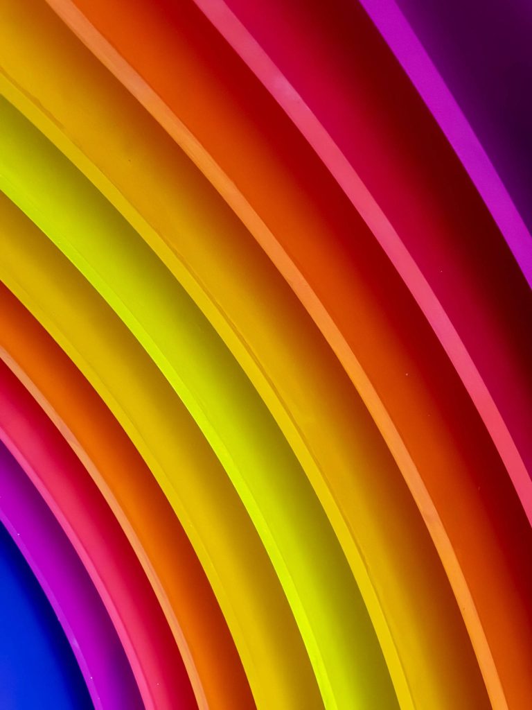 Vibrant neon rainbow wallpaper with glossy curved bands in bold saturated colors background