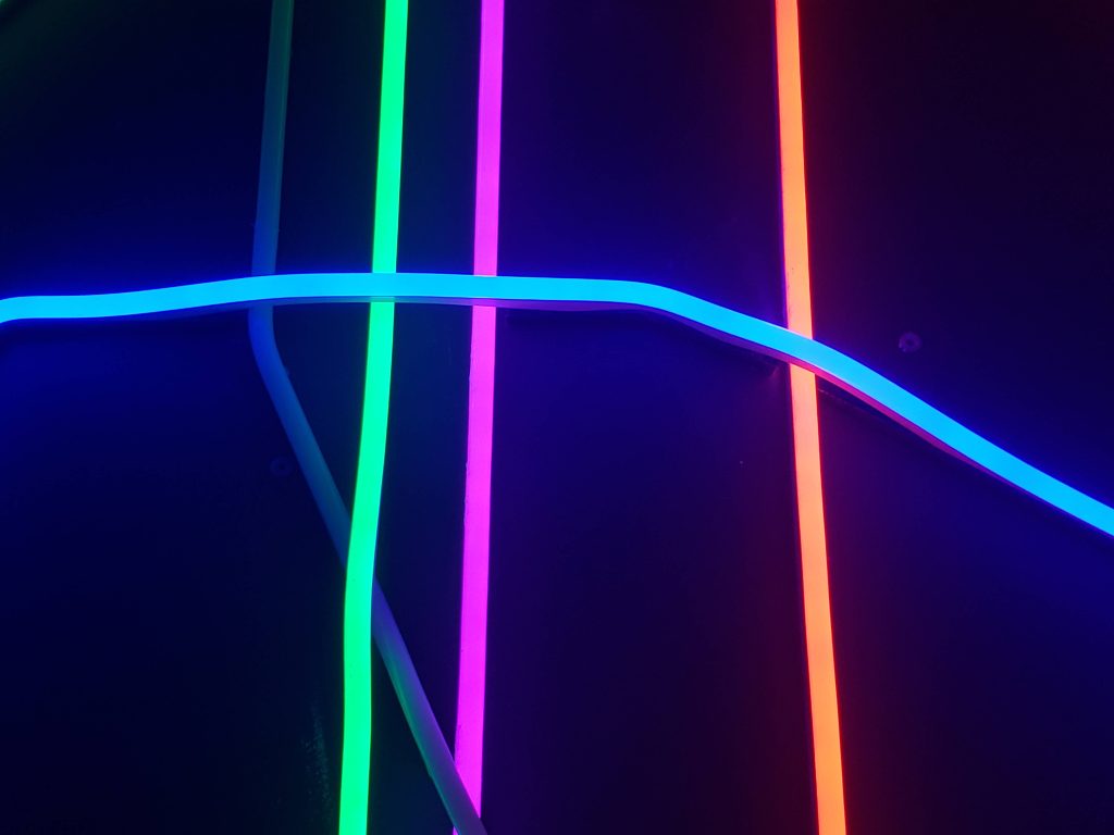 Neon wallpaper with vibrant green magenta red vertical lines and blue horizontal strip on black background