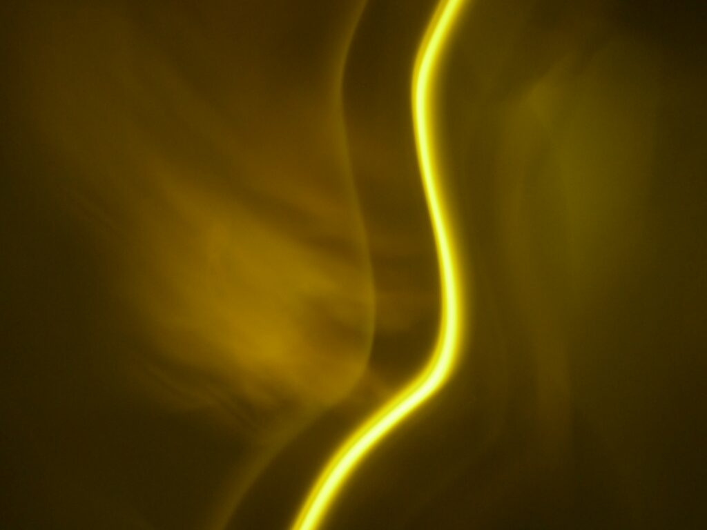Vibrant Neon Yellow Wavy Wallpaper on Dark Abstract Background