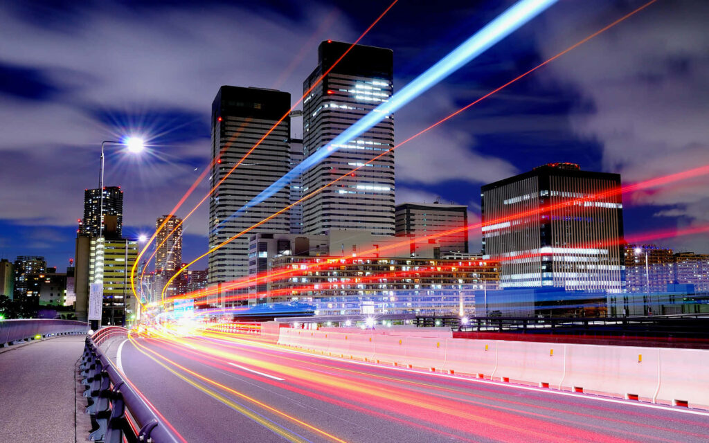 Vibrant Night Highway Wallpaper: Colorful Light Trails & Skyscrapers