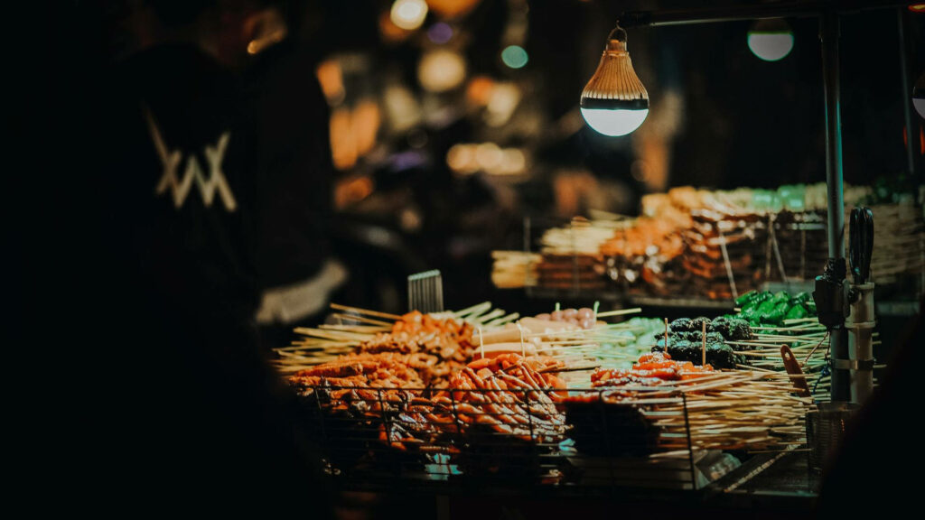 Vibrant Night Market: Delicious Skewered Snacks Wallpaper Background