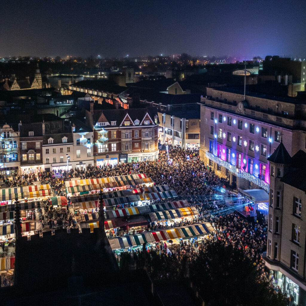 Vibrant Cambridge Night View: Colorful Market Stalls & Festive Lights Wallpaper