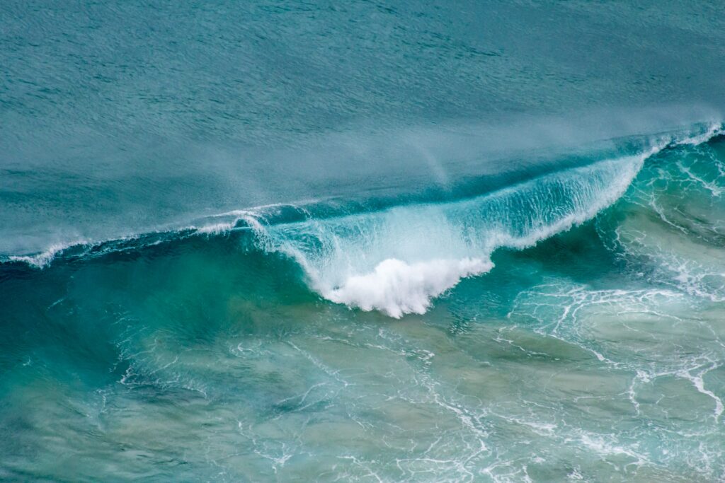 Vibrant blue ocean wave crashing with white foam high resolution dynamic sea wallpaper background