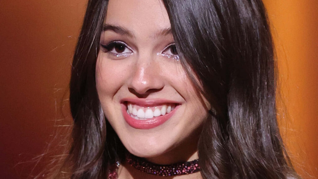 Olivia Rodrigo Vibrant Wallpaper: Radiant Smile & Dynamic Background