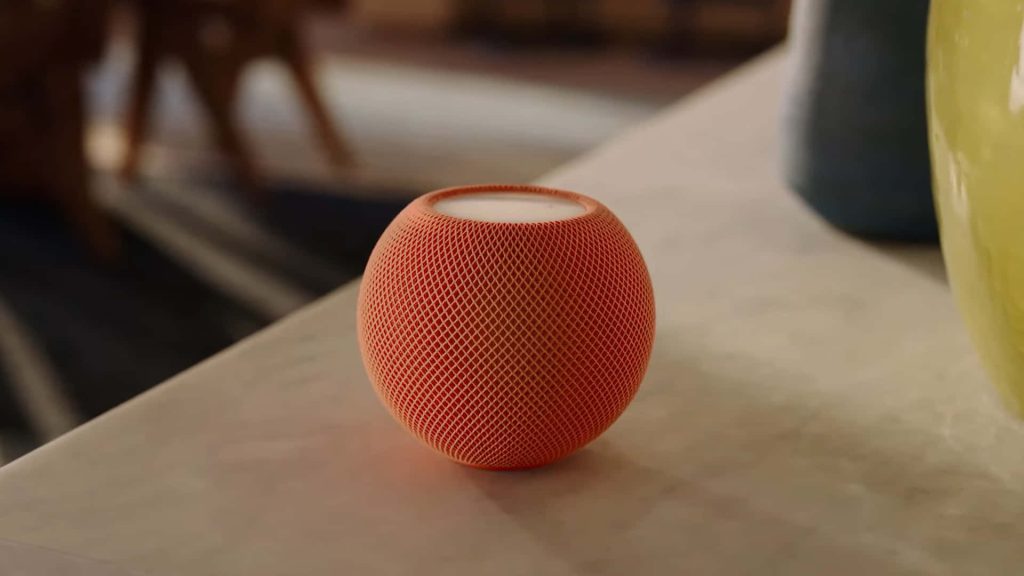 Vibrant orange Apple HomePod mini on smooth surface with warm lighting and modern mesh design Wallpaper
