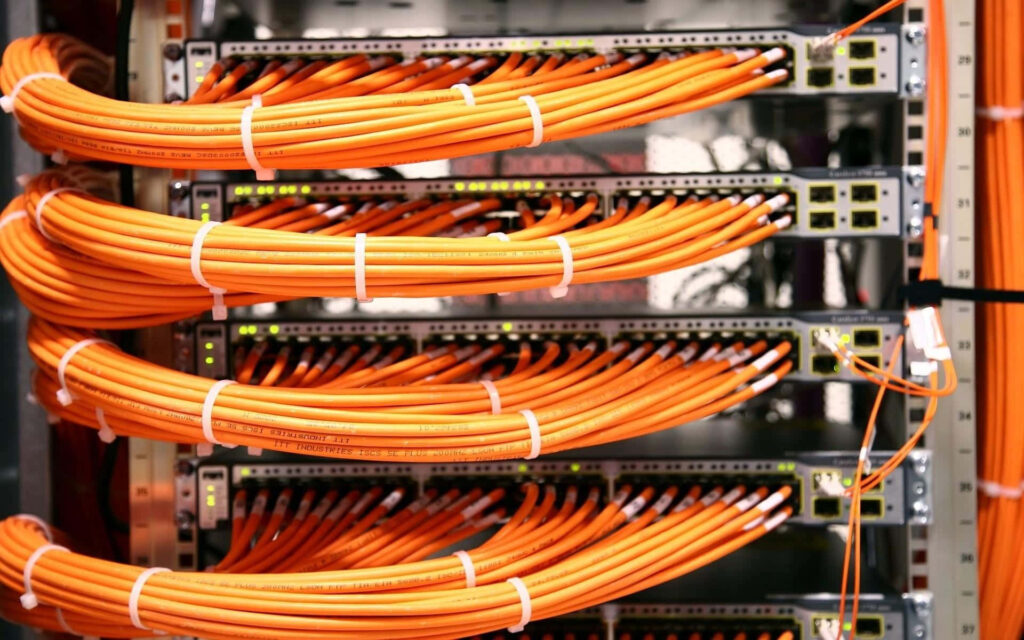 Close-up of organized orange Ethernet cables connected to network switches in a data center Wallpaper