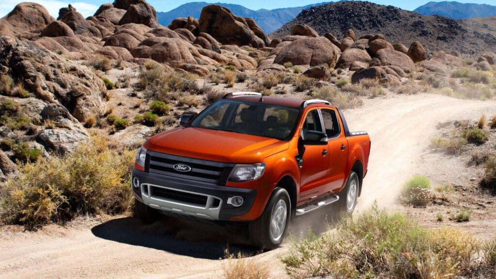 Orange Ford Ranger driving rugged desert trail with rocky mountains off-road adventure wallpaper