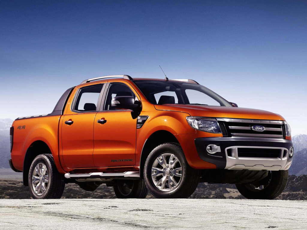 Vibrant orange Ford Ranger parked on rugged mountainous terrain showcasing powerful design Wallpaper