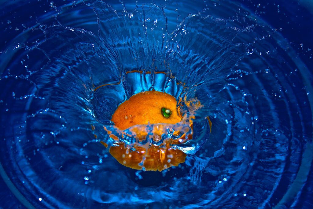 Vibrant Orange Fruit Splash Wallpaper Against Bold Blue Background