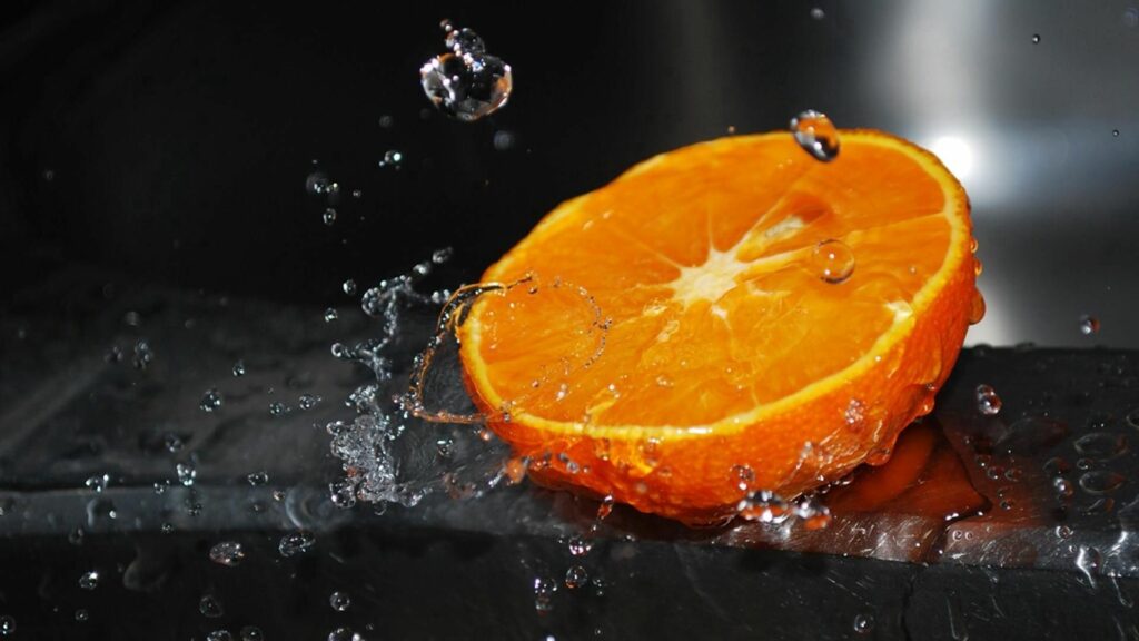 Juicy Orange Half Wallpaper with Dynamic Water Splash Background