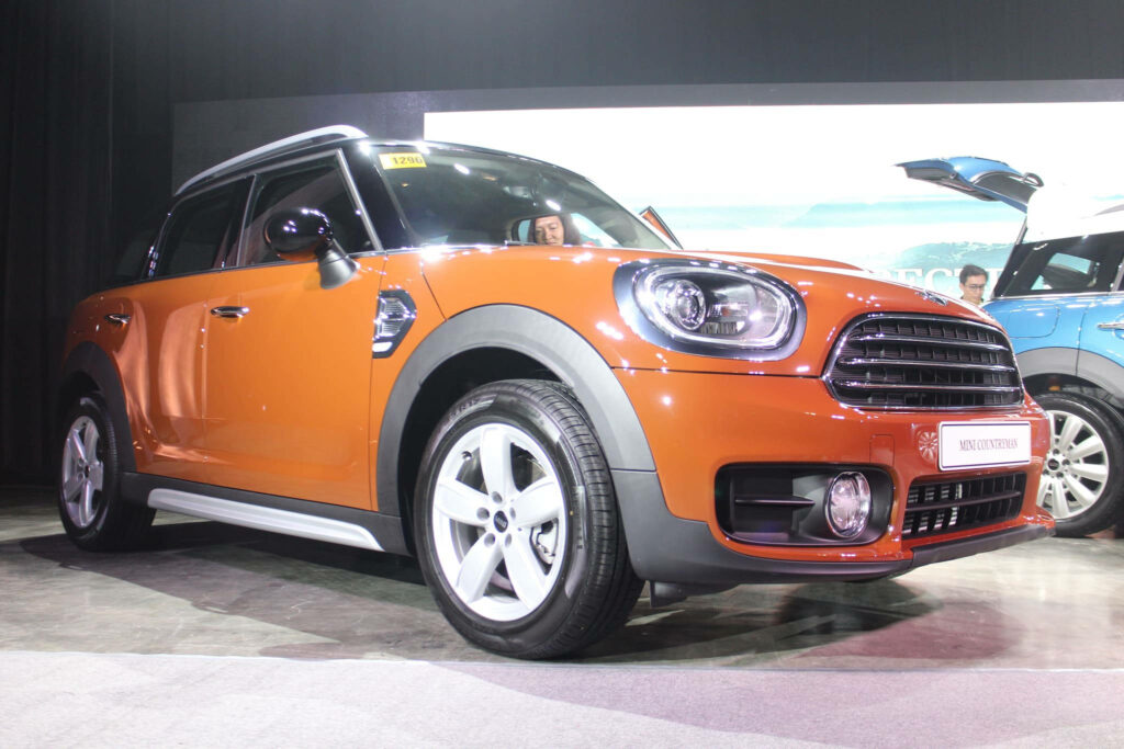 Vibrant orange Mini car under showroom lights modern automotive wallpaper background