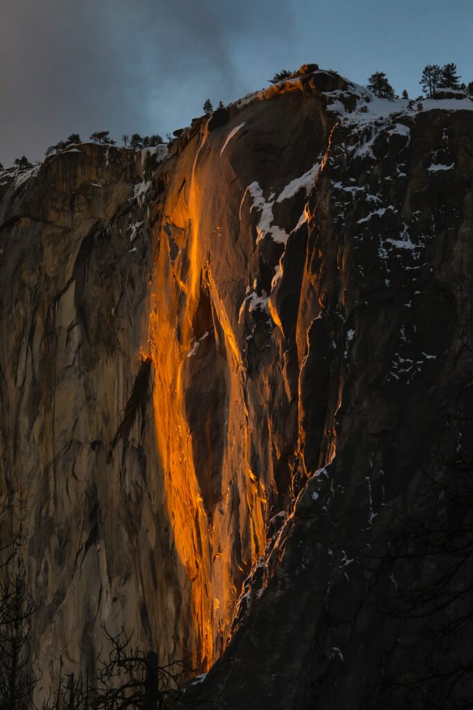 Dramatic mountain peak with rugged rocks and orange glow against dark sky wallpaper background