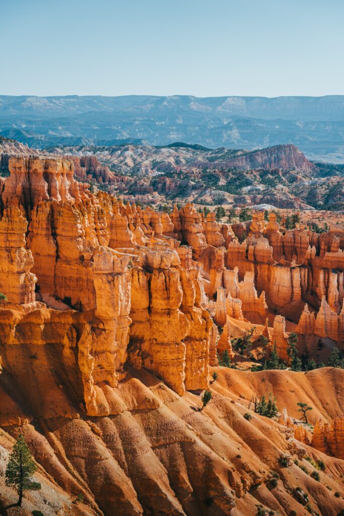 Vivid orange red canyon with jagged rocks towering peaks and blue mountains desert landscape wallpaper
