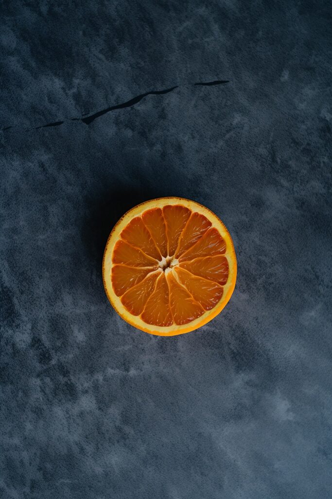 Vibrant Orange Slice on Textured Blue Wallpaper Background