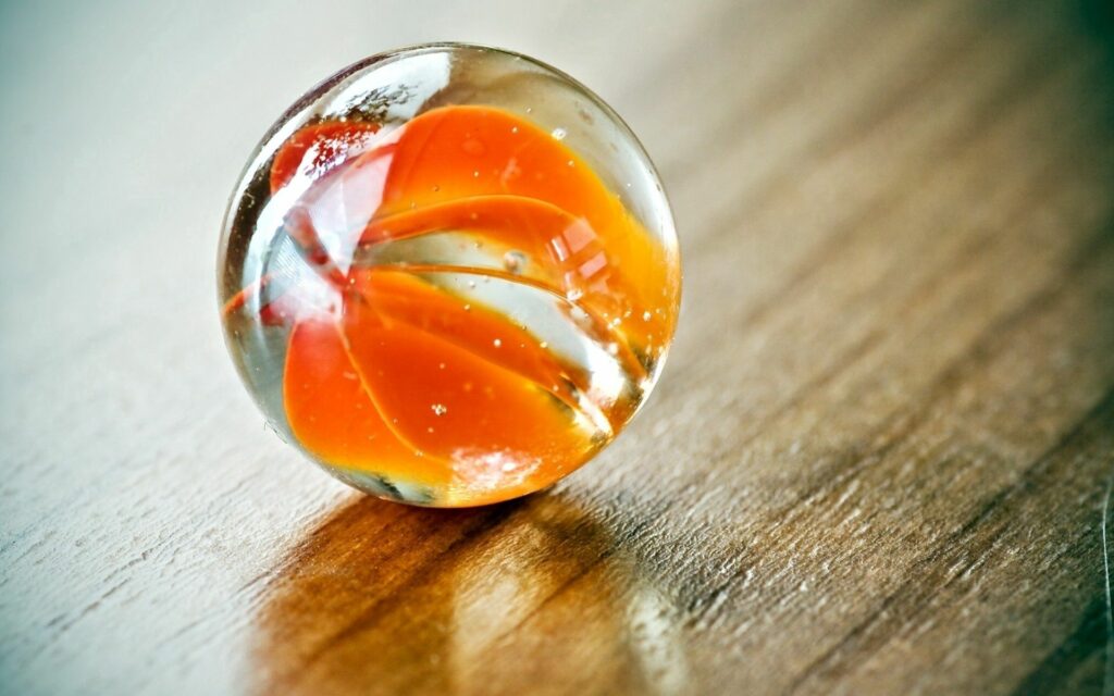 Vibrant Orange Swirl Glass Marble on Wooden Texture Wallpaper