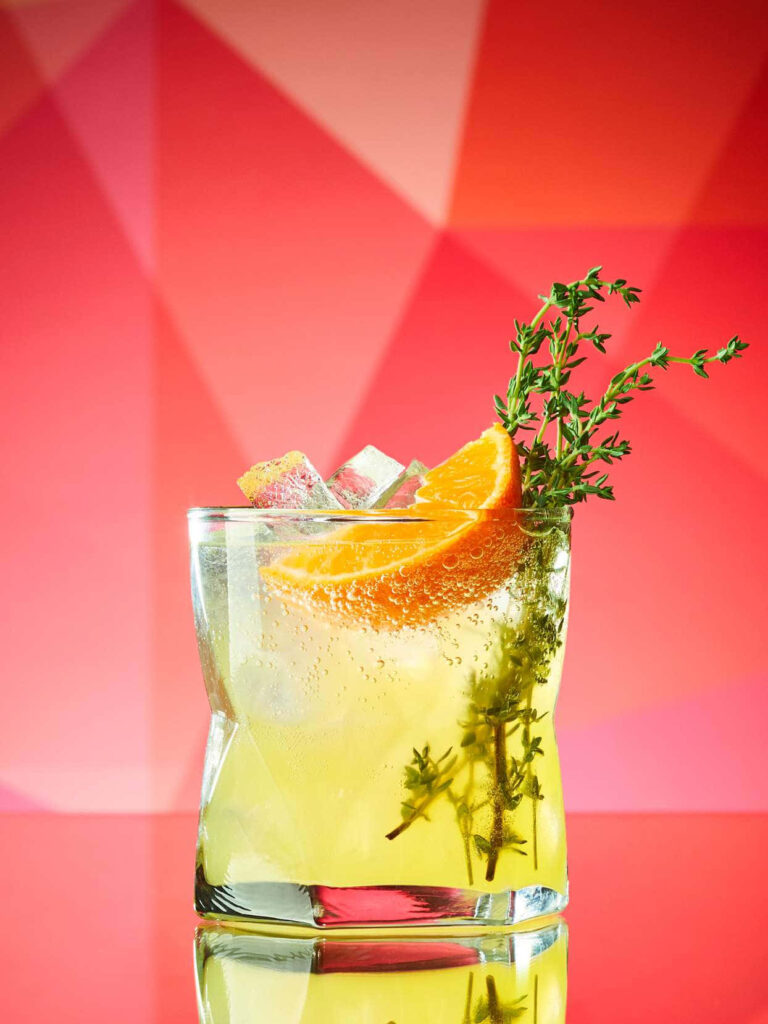 Refreshing Orange Thyme Cocktail Wallpaper with Dynamic Geometric Background