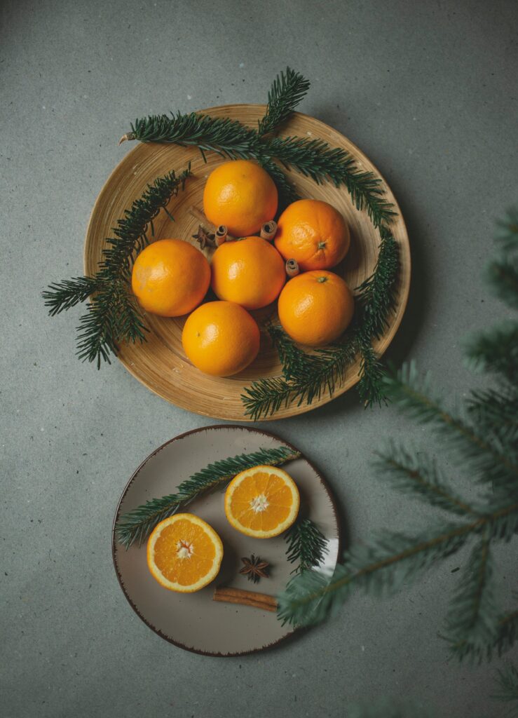 Cozy Wallpaper: Fresh Oranges on Plates with Cinnamon & Fir Branches