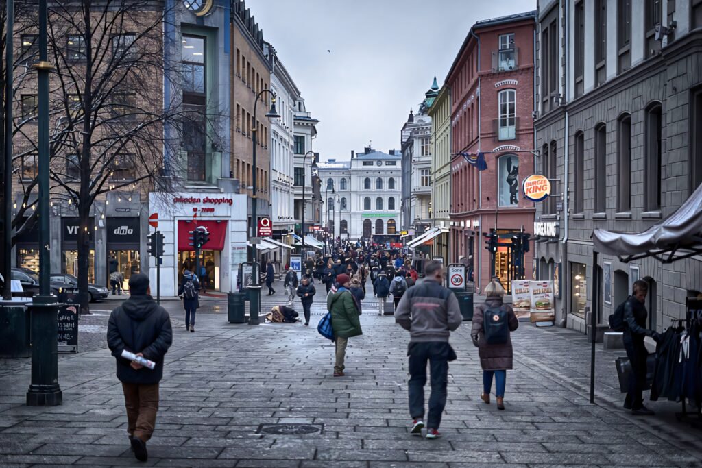 Vibrant Oslo Street Scene: Shops, People & Historic Architecture Wallpaper