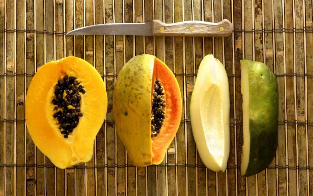 Vibrant Papaya Wallpaper: Sliced Fruits on Rustic Bamboo Background