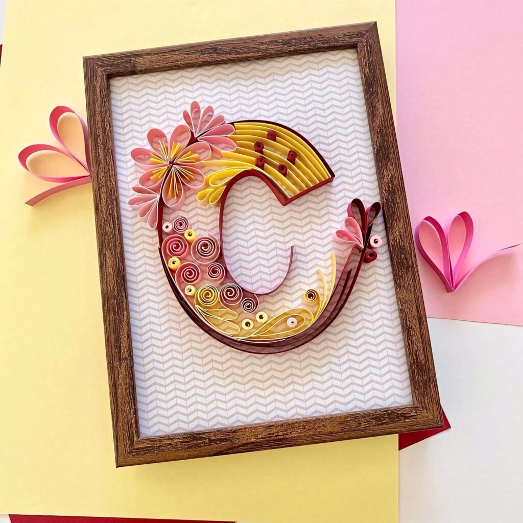 Colorful paper quilled letter C in yellow pink and red framed on textured background wallpaper