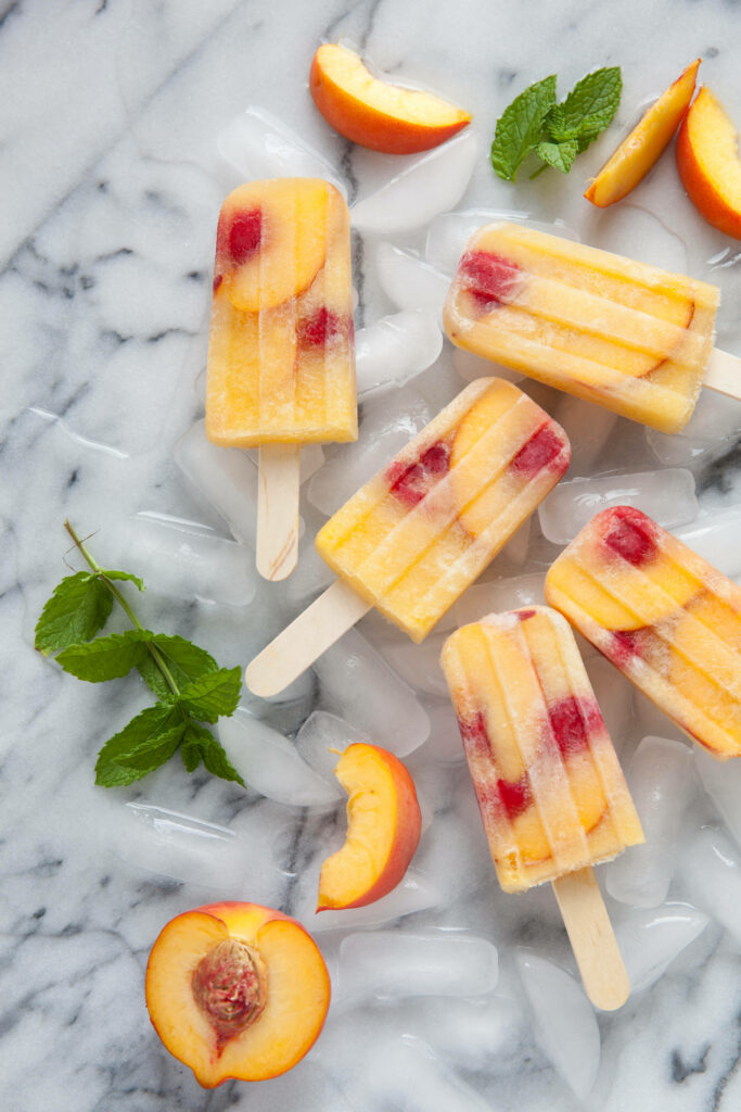 Vibrant ice cream popsicles with peach slices berries mint and ice cubes summer wallpaper background