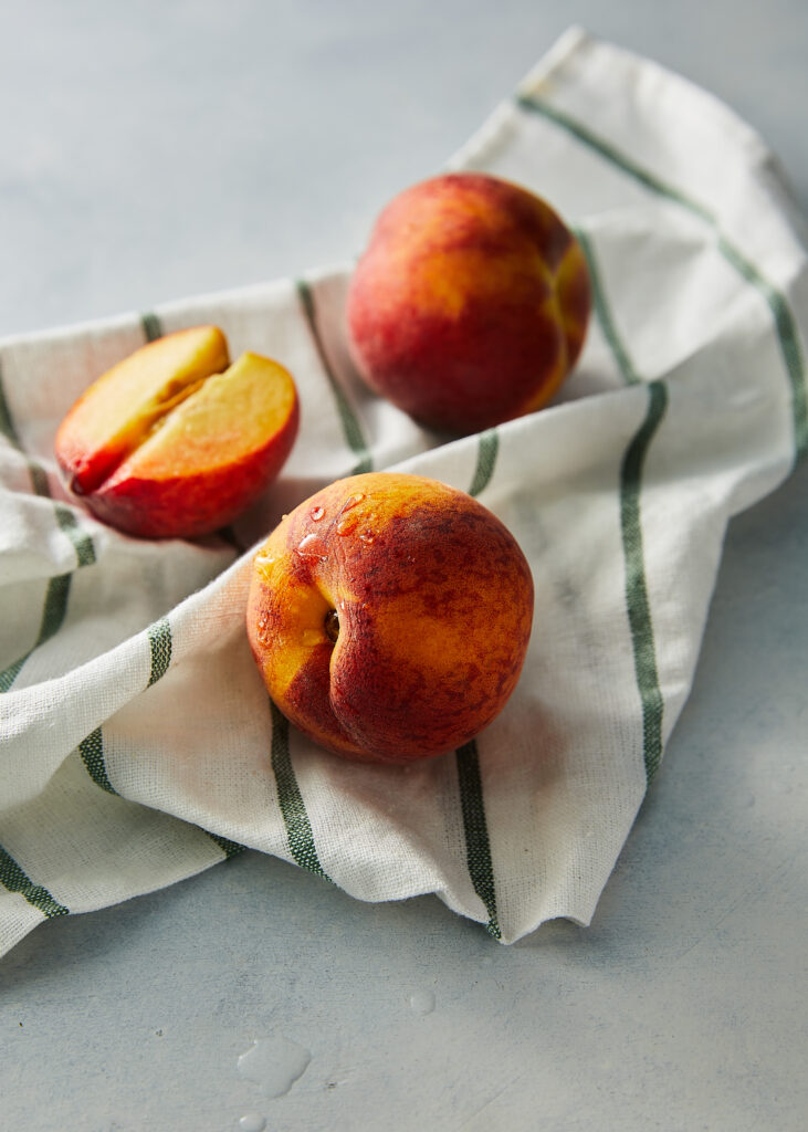 Vibrant Ripe Peaches on Striped Towel - Textured Wallpaper Background