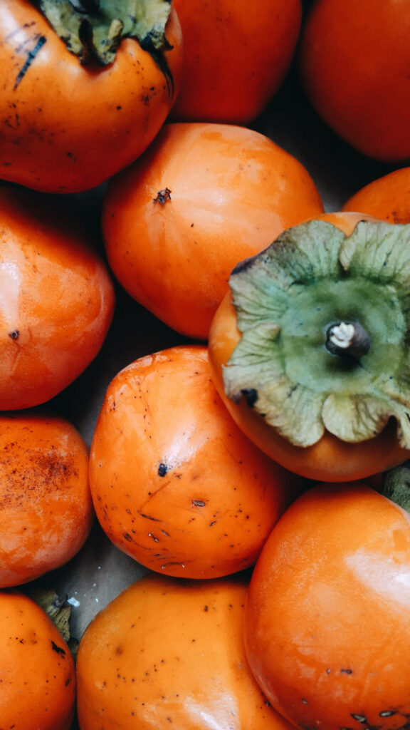 Vibrant Persimmon Fruit Wallpaper: Close-Up of Ripe Oranges & Greens