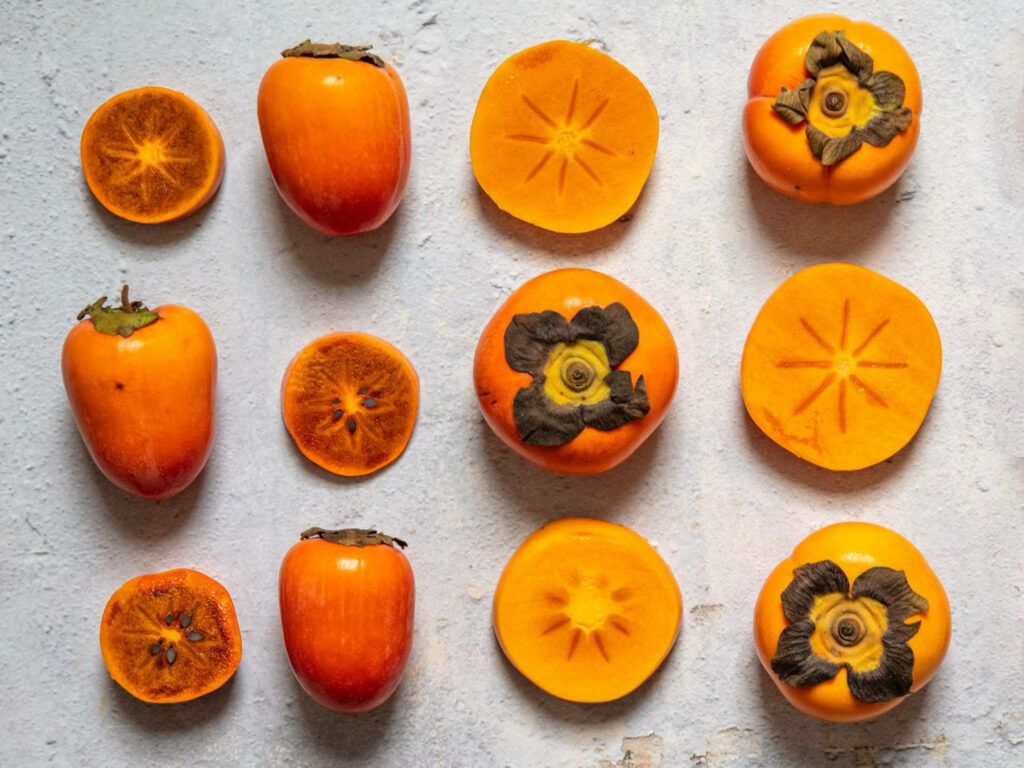Vibrant Persimmons Wallpaper: Fresh Fruit Decor on Light Background