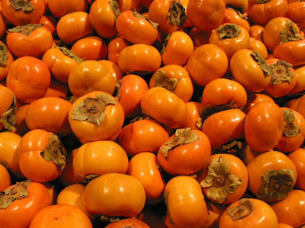 Vibrant Persimmon Wallpaper: Fresh Orange Fruits & Leafy Tops Background