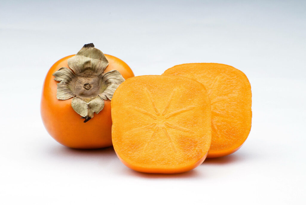 Vibrant Persimmon Wallpaper: Ripe Fruit & Slices on White Table