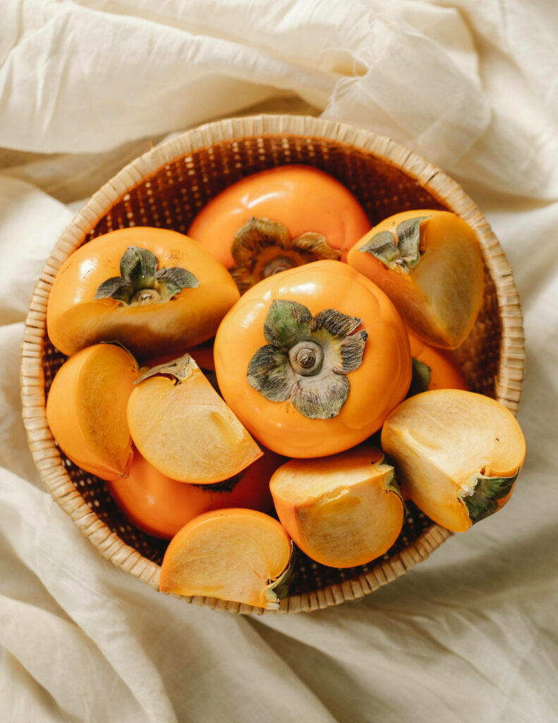 Vibrant Persimmon Wallpaper: Ripe Fruit on Soft Fabric Background