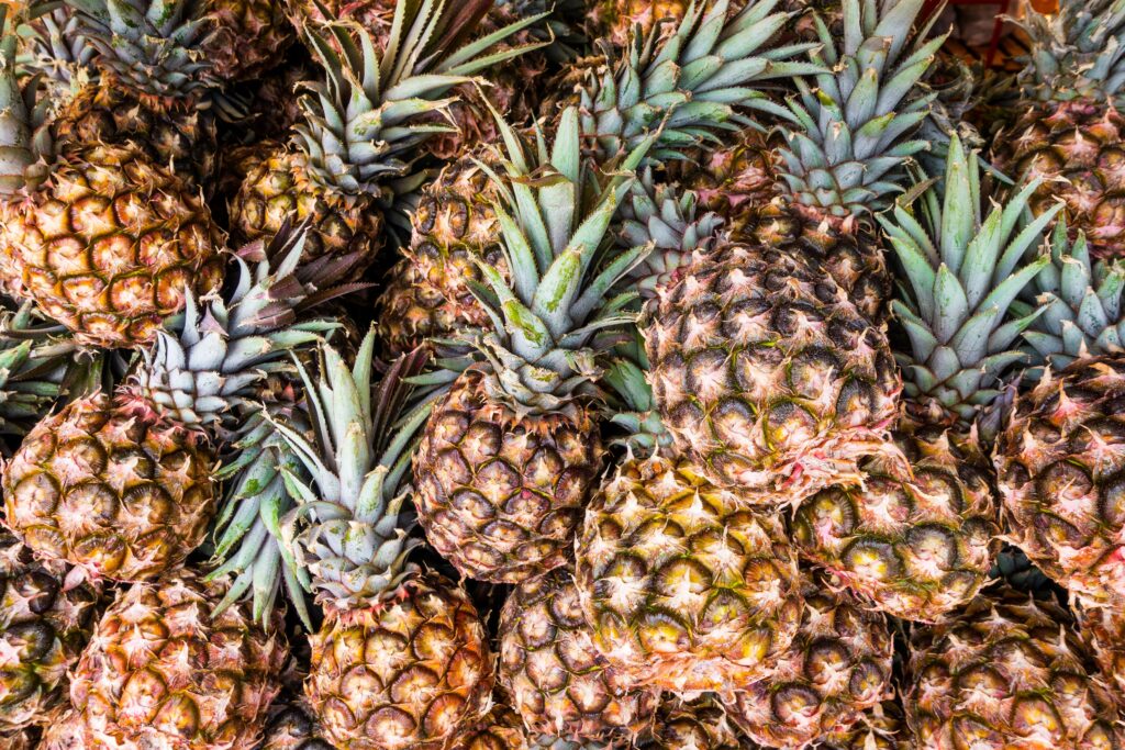 Vibrant Pineapple Close-Up Wallpaper: Textured Skin & Green Tops