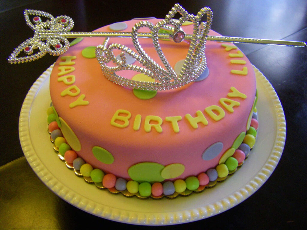 Vibrant Pink Birthday Cake with Tiara and Colorful Candies Background Wallpaper