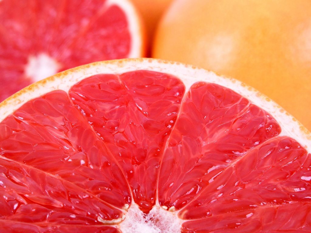 Close-up of juicy pink grapefruit segments vibrant fresh citrus wallpaper background