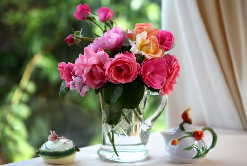 Elegant Pink & Peach Roses in Glass Vase: Serene Garden Scene Wallpaper