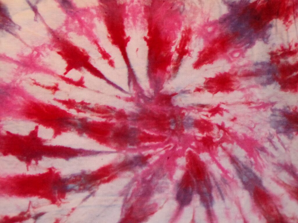 Abstract tie-dye wallpaper with swirling pink red and purple bursts on soft white background